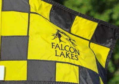 A checkered yellow and black flag is outside on the green at Falcon Lakes Golf Course.
